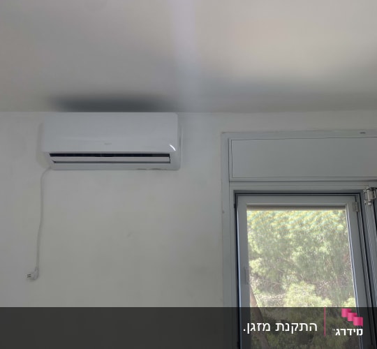 מזגן מותקן על קיר ליד חלון פתוח